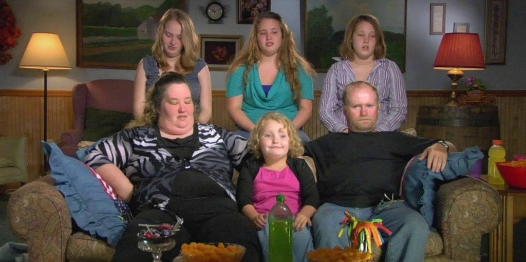Six family members pose sitting on and standing behind a couch
