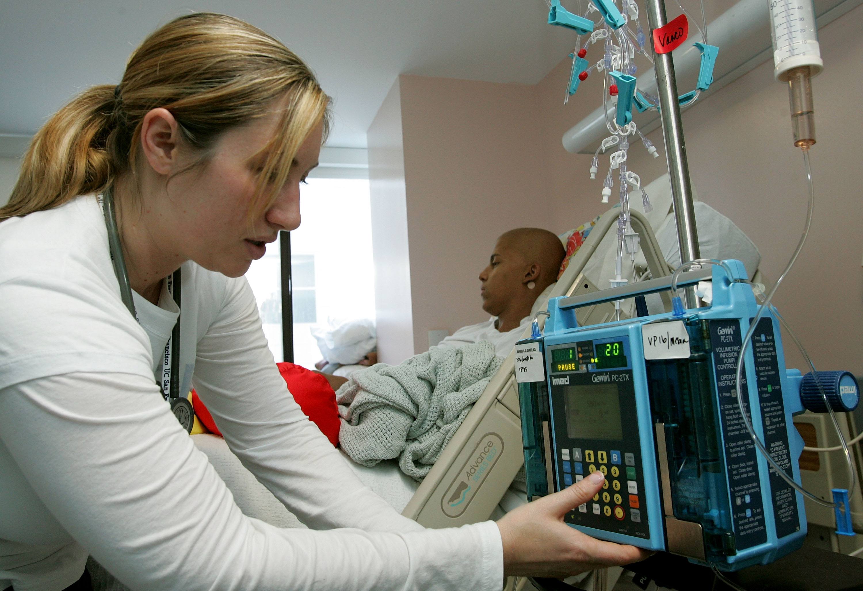 Registered nurse Autumn Small adjusts an IV drip machine for an eighteen-year-old cancer patient