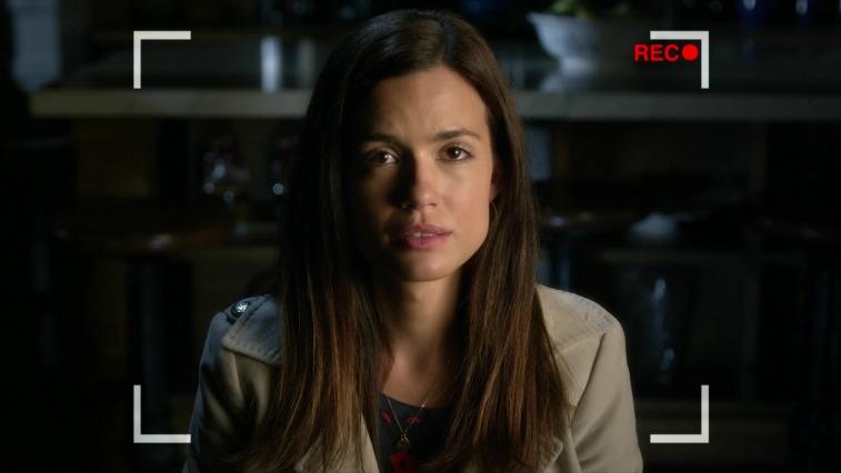 Brunette woman is talking to a camera that is recording in a kitchen