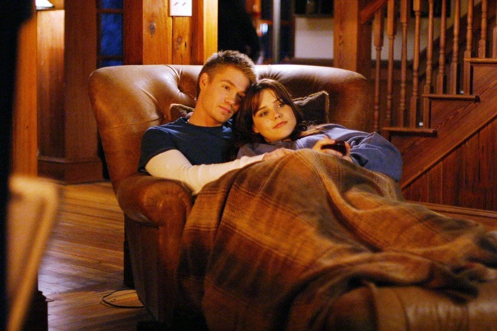 Lucas and Brooke cuddling on a chair under a blanket.