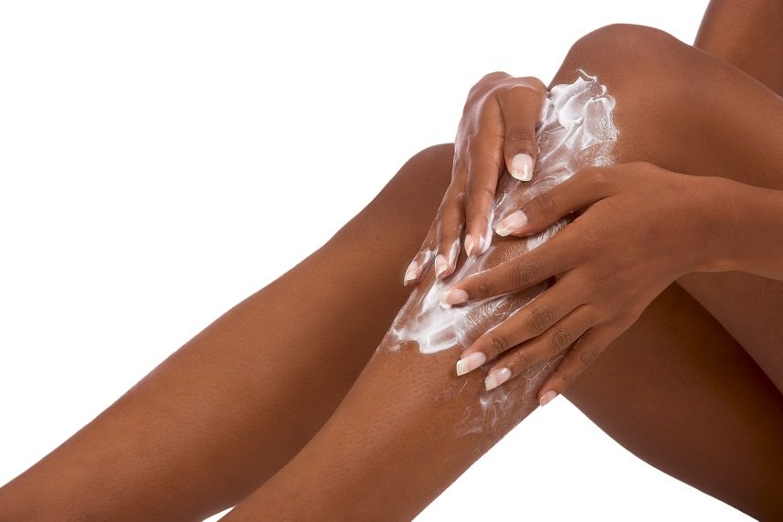 Woman applying lotion to her legs.