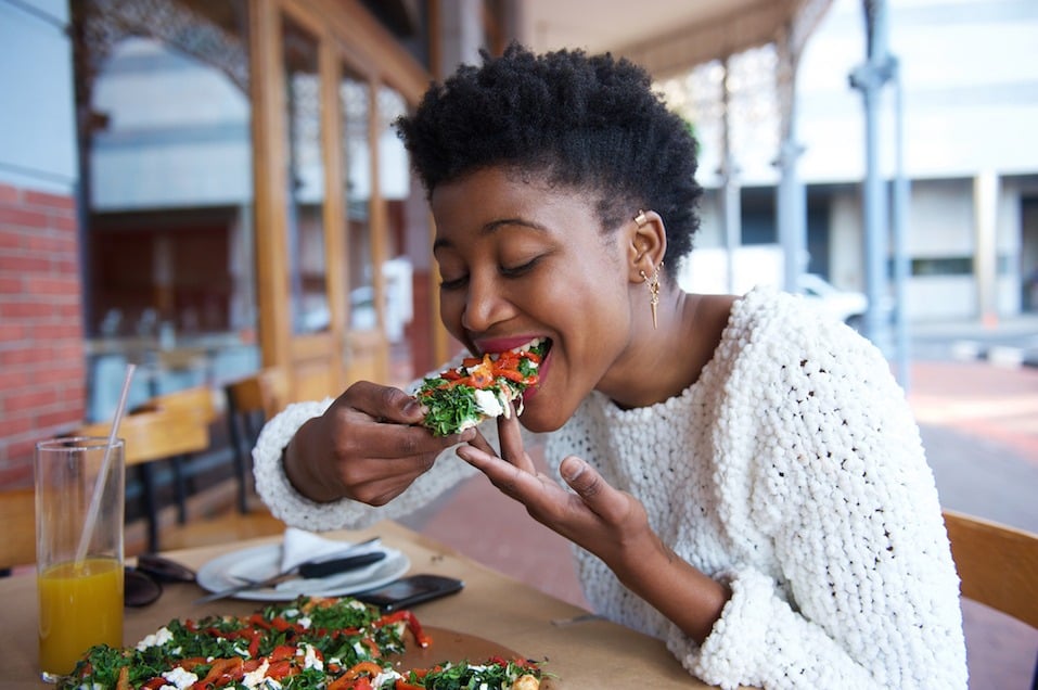African american woman eating pizza