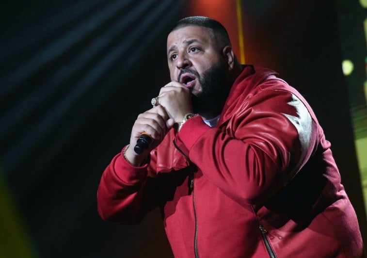 DJ Khaled holds a microphone while performing on stage.