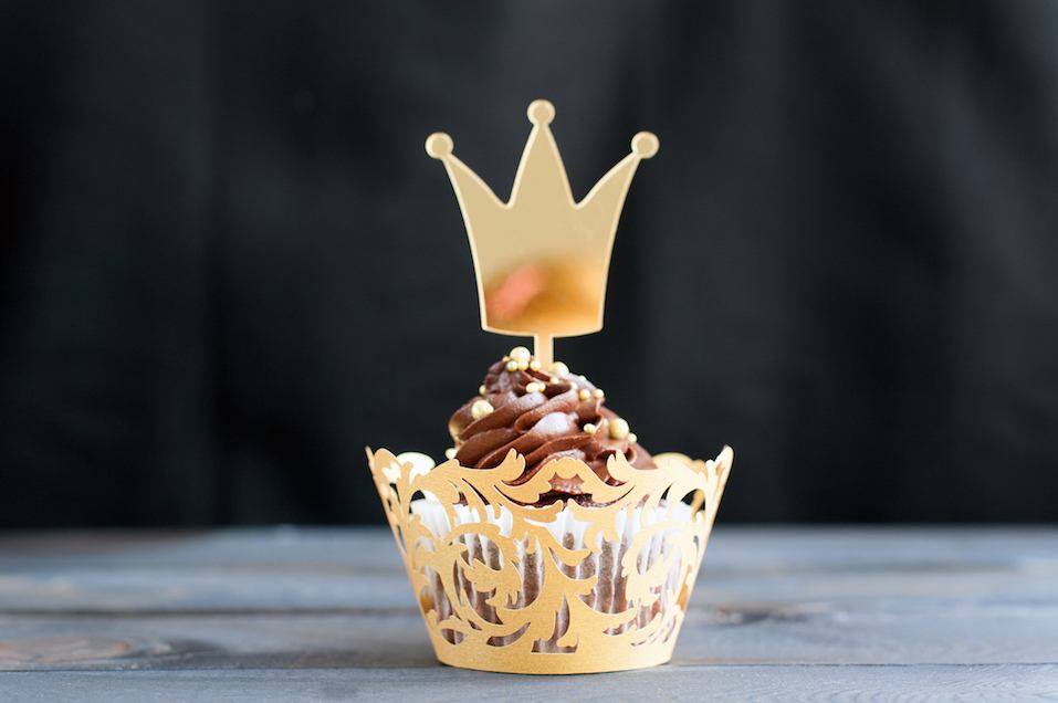 cupcakes with chocolate cream and topper in the shape of a gold crown