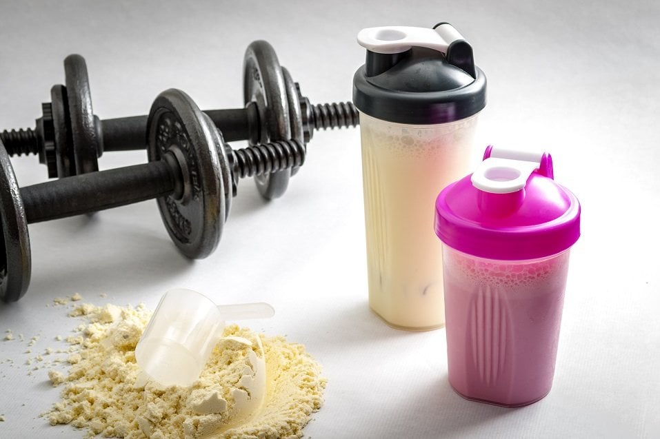 Dumbbells, protein shakers and a scoop in protein powder Dumbbells, protein shakers and a scoop in protein powder