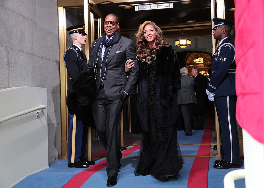 Jay-Z and Beyonce locking arms, smiling, and walking togethe