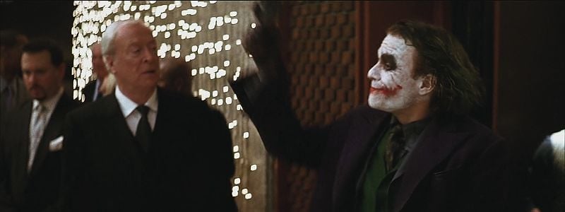 Heath Ledger holding a gun in the air as The Joker