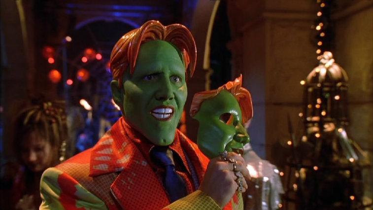 Jamie Kennedy in 'Son of the Mask' with a green face smiling and holding a masquerade-style mask