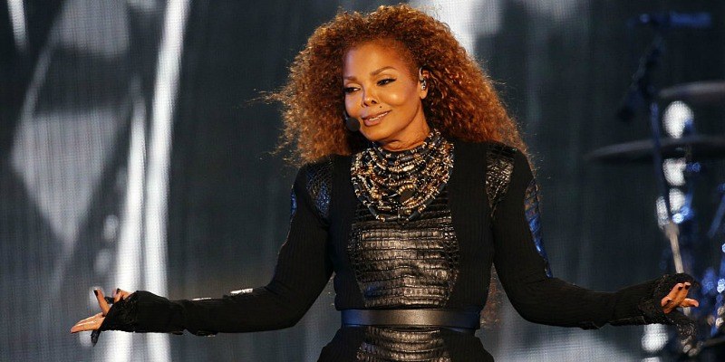 Janet Jackson in a black dress singing on stage
