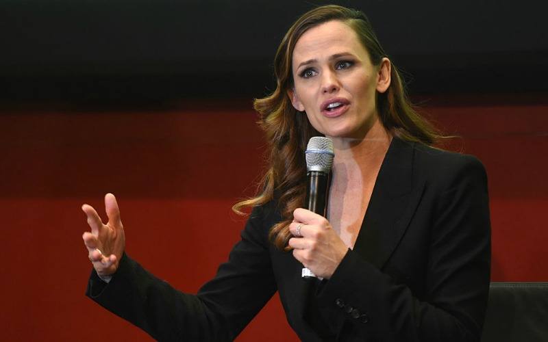 Jennifer Garner speaking into a microphone while wearing a black suit.