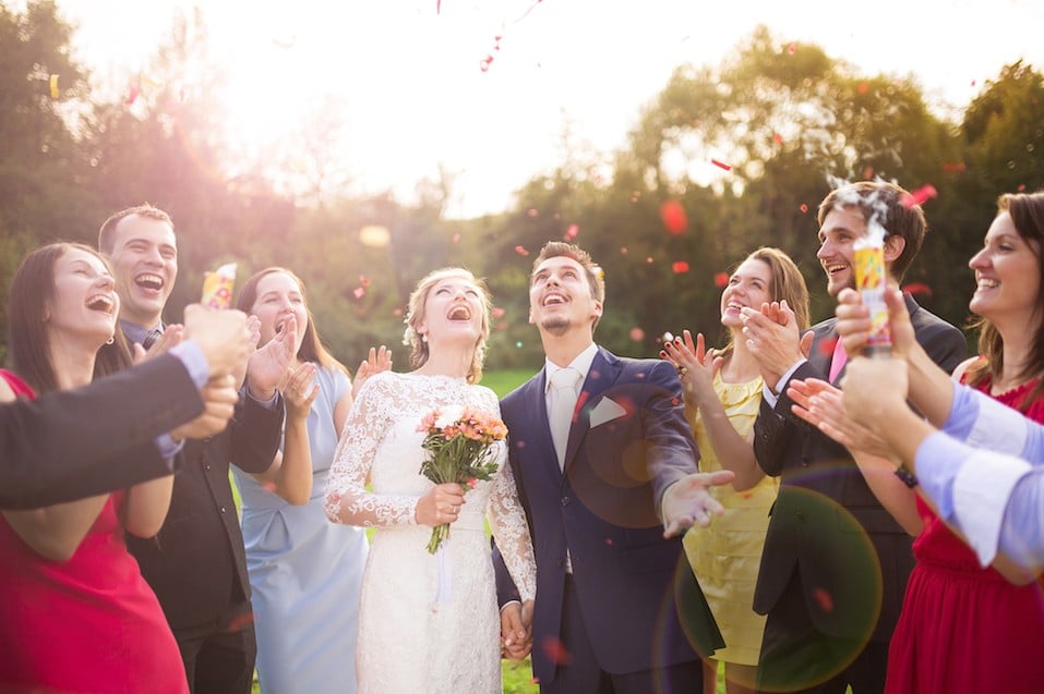 newlywed couple and their friends at the wedding party showered with confetti in green sunny park newlywed couple and their friends at the wedding party showered with confetti in green sunny park
