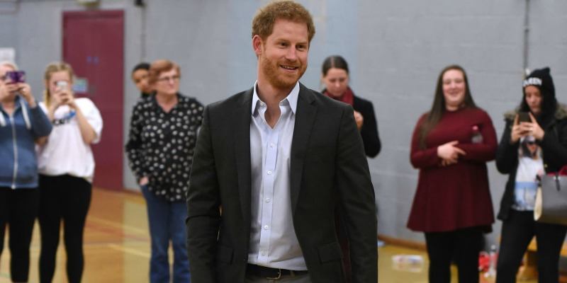Prince Harry is smiling and wearing a suit in a gymnasium. Prince Harry is smiling and wearing a suit in a gymnasium.