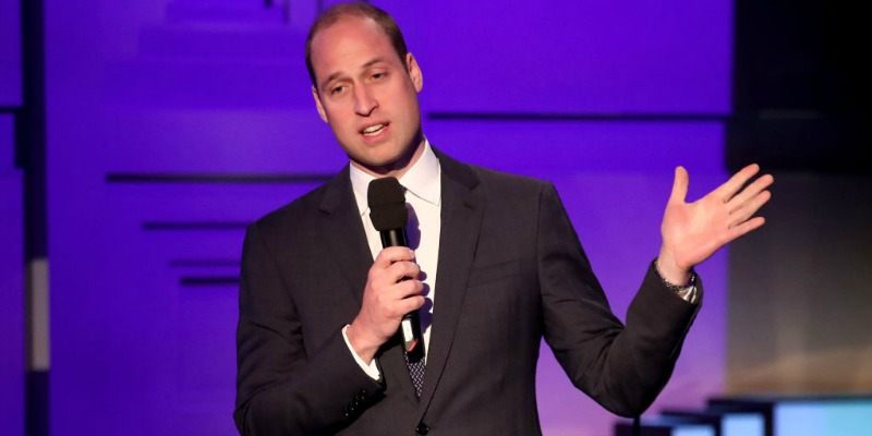 Prince William is holding a microphone and talking on stage.