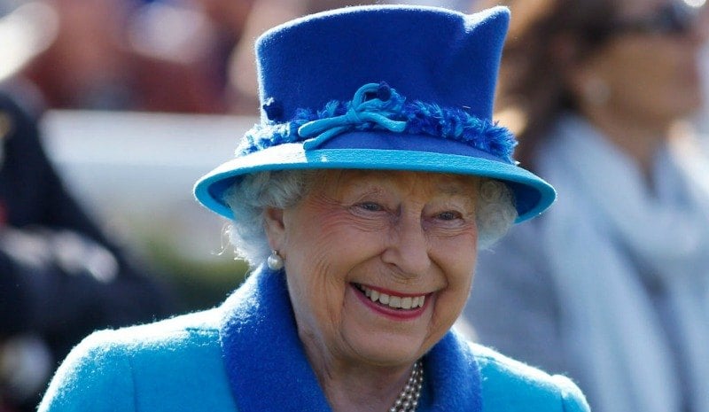 Queen Elizabeth II is wearing a blue suit dress and a hat.