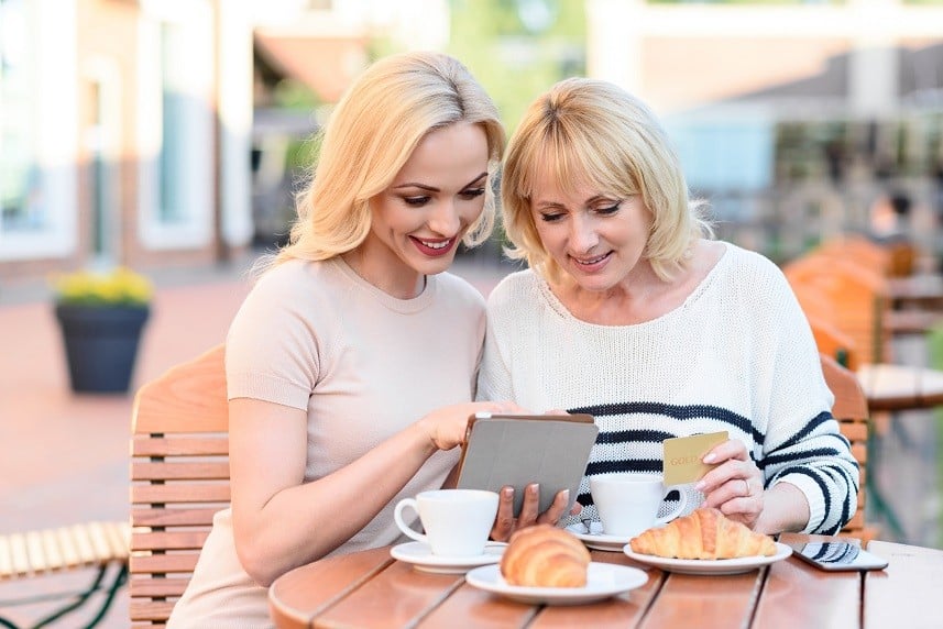 Cheerful mother and daughter are using tablet and smiling