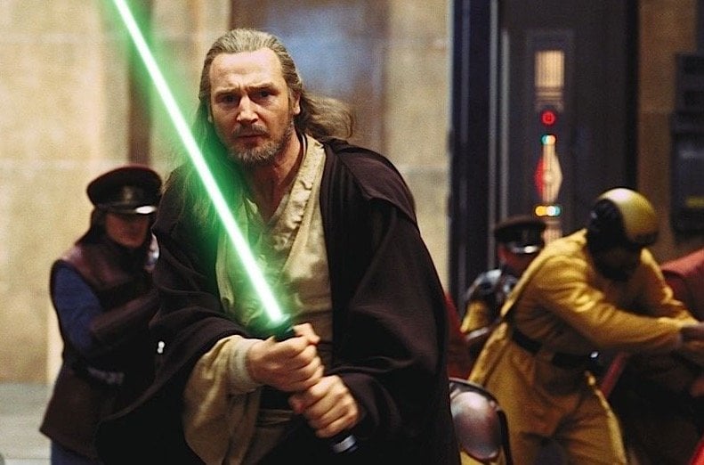 Qui Gon holds his lightsaber out in front of his body in The Phantom Menace