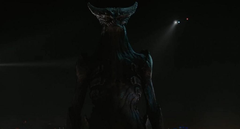 The monster from Colossal standing with its arms at either side