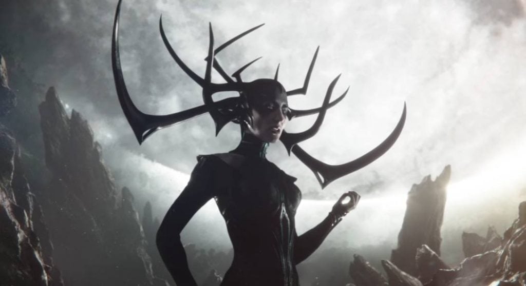 Hela with her left hand up, and her antler-helmet on