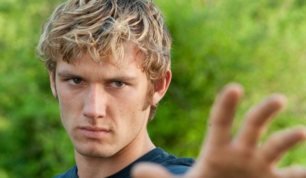 Alex Pettyfer with his hand out, scowling