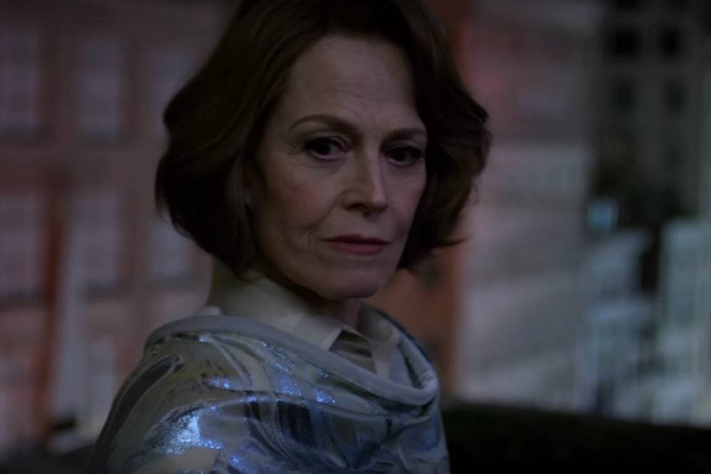 Sigourney Weaver, wearing a white dress and looking to the right of the frame