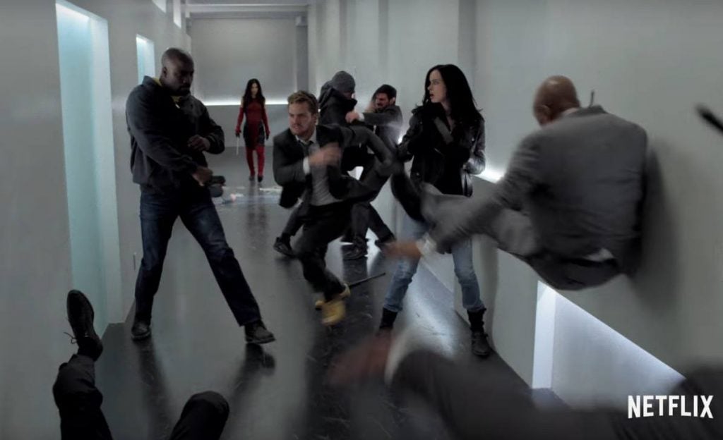 The Defenders fighting in a white hallway together
