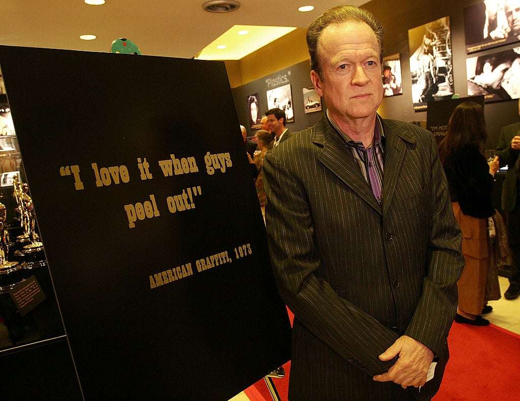 Screenwriter Willard Huyck poses beside a poster that bears a famous line from his film "American Graffiti"