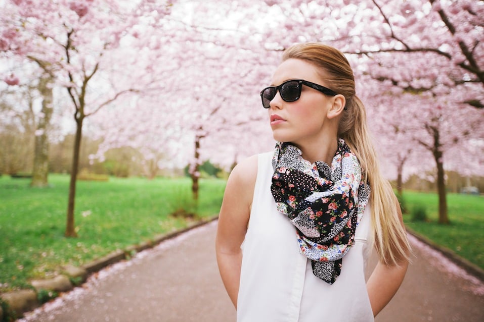 Stylish young woman posing at the spring blossom garden.