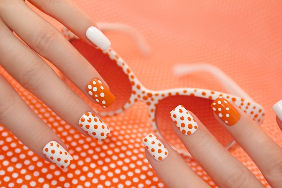 Sunny orange manicure with dots on the women's nails closeup.