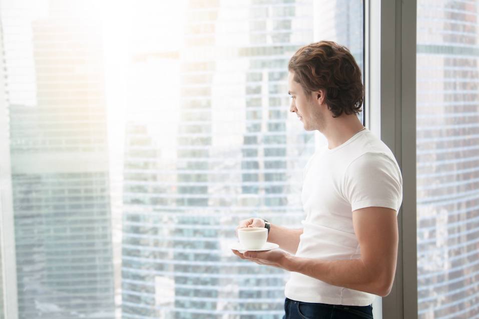 Young handsome man near full length window