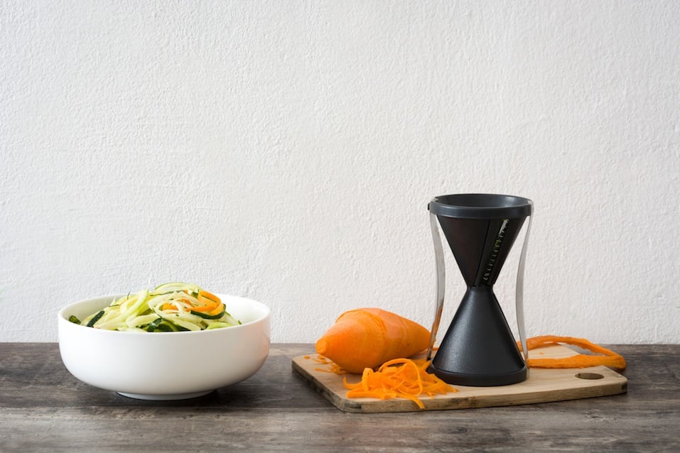 Zucchini and carrot noodles in a bowl, on wooden table