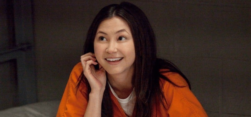 In a scene from Orange Is the New Black, Brook Soso is in an orange jumpsuit and is smiling.