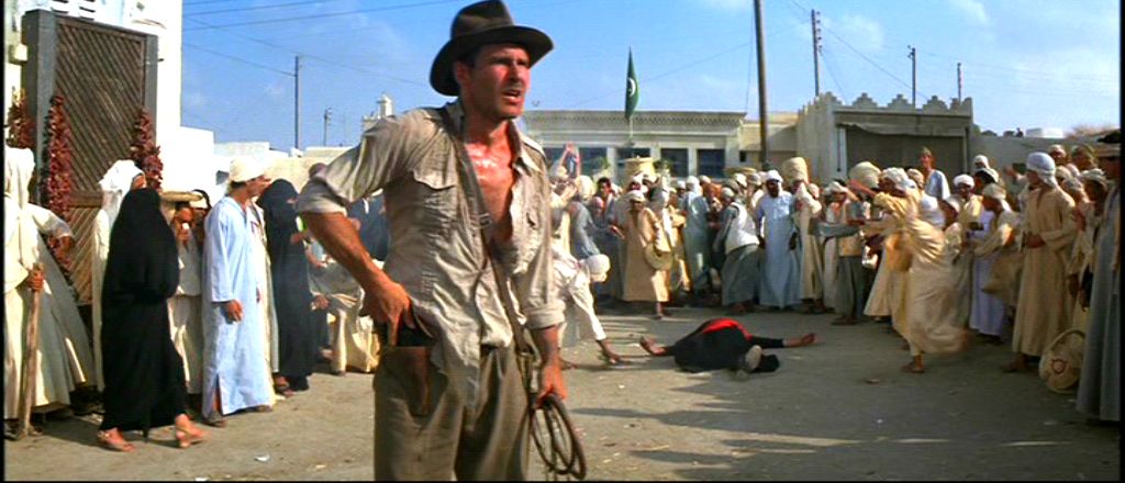 Harrison Ford holstering his gun in Raiders of the Lost Ark with a whip in his left hand