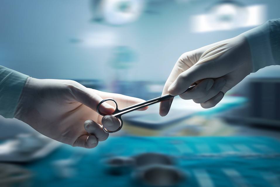 Close-up of surgeons hands holding surgical scissors and passing surgical equipment , motion blur background.