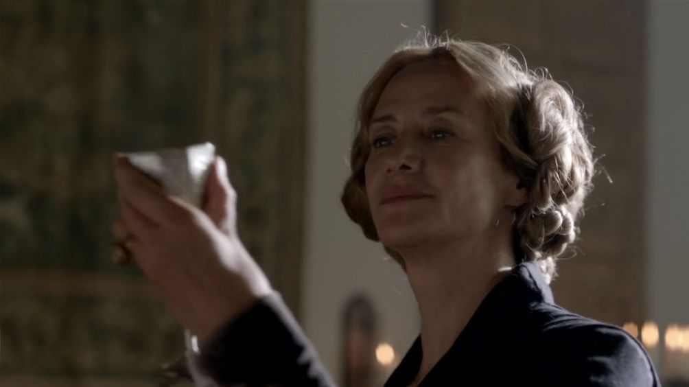 Janet McTeer holds up a chalice, while smiling