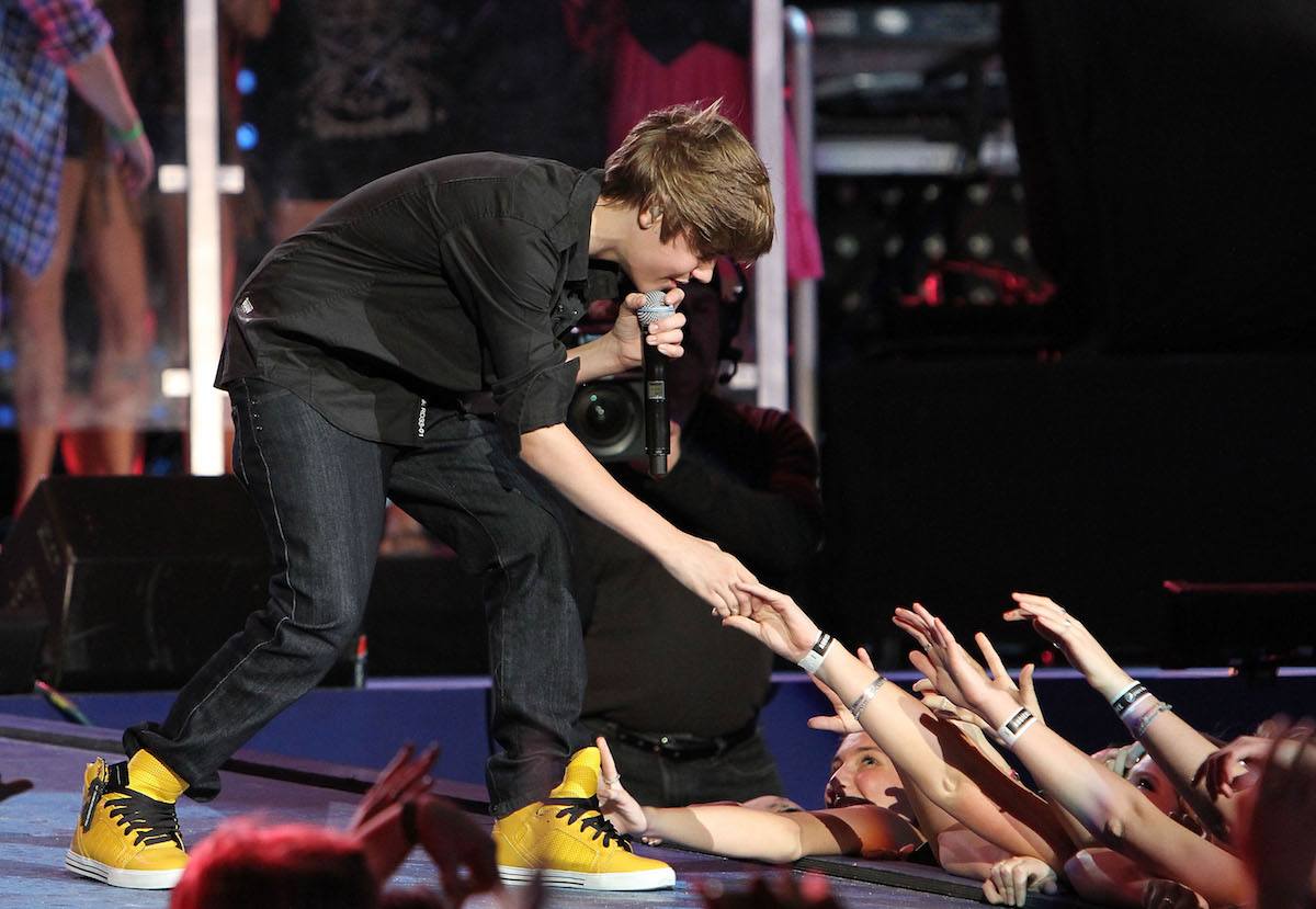 Justin Bieber leans down to shake fans' hands during a 2010 performance.
