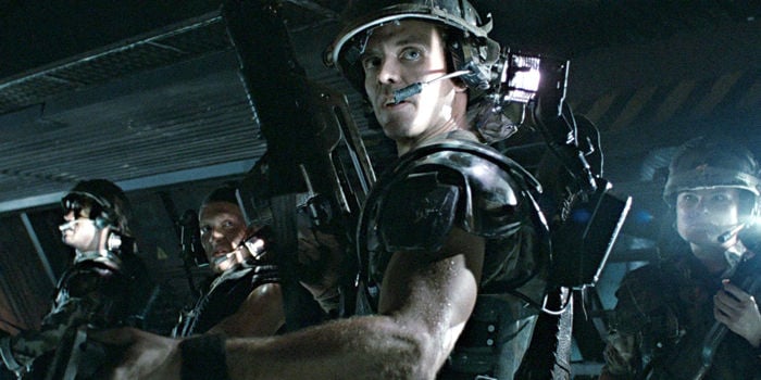 Michael Biehn dressed as a soldier, looking behind his left shoulder in a dark corridor