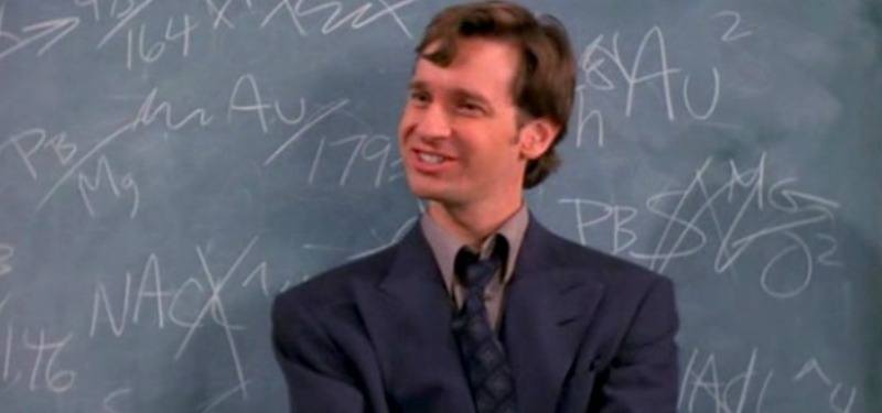 Paul Feig is in a suit and standing in front of a chalkboard.