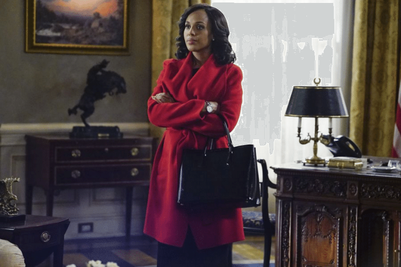 Kerry Washington's Olivia Pope stands next to a desk in a red coat in a scene from Scandal
