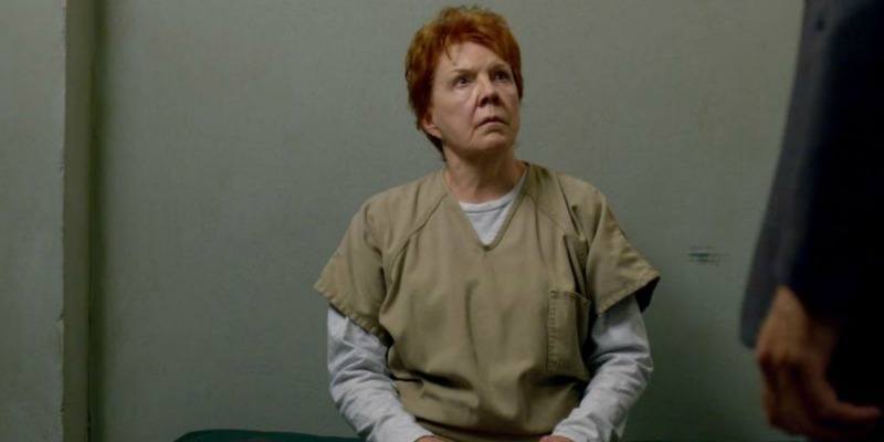 Sister Ingalls is sitting on a bed looking up at an officer.