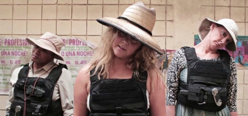 Wanda Sykes, Amy Schumer, and Joan Cusack have their heads tilted to one side and are wearing bulletproof vests.