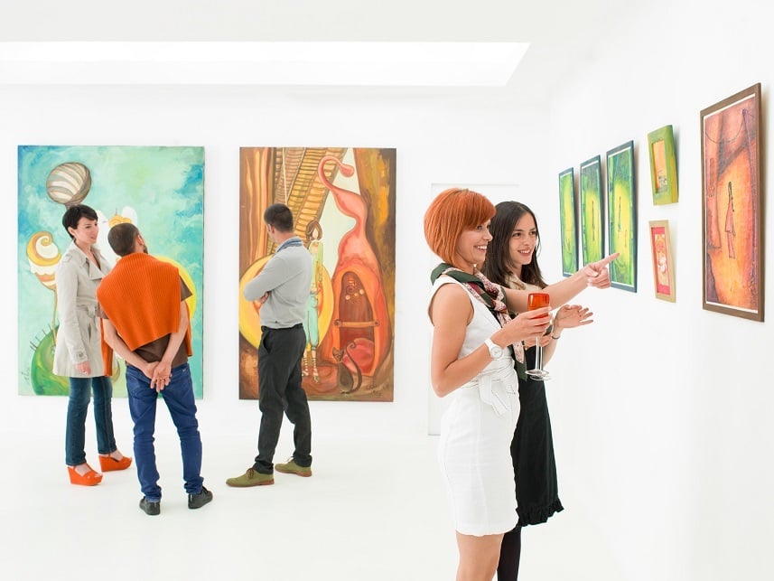 people in an art gallery talking about the colorful paintings