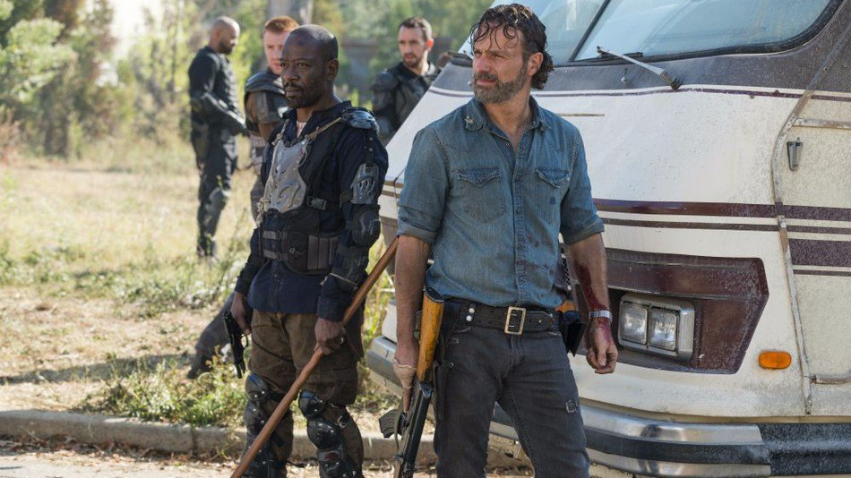 Rick and Morgan both looking off into the distance, holding weapons and standing in front of an RV.