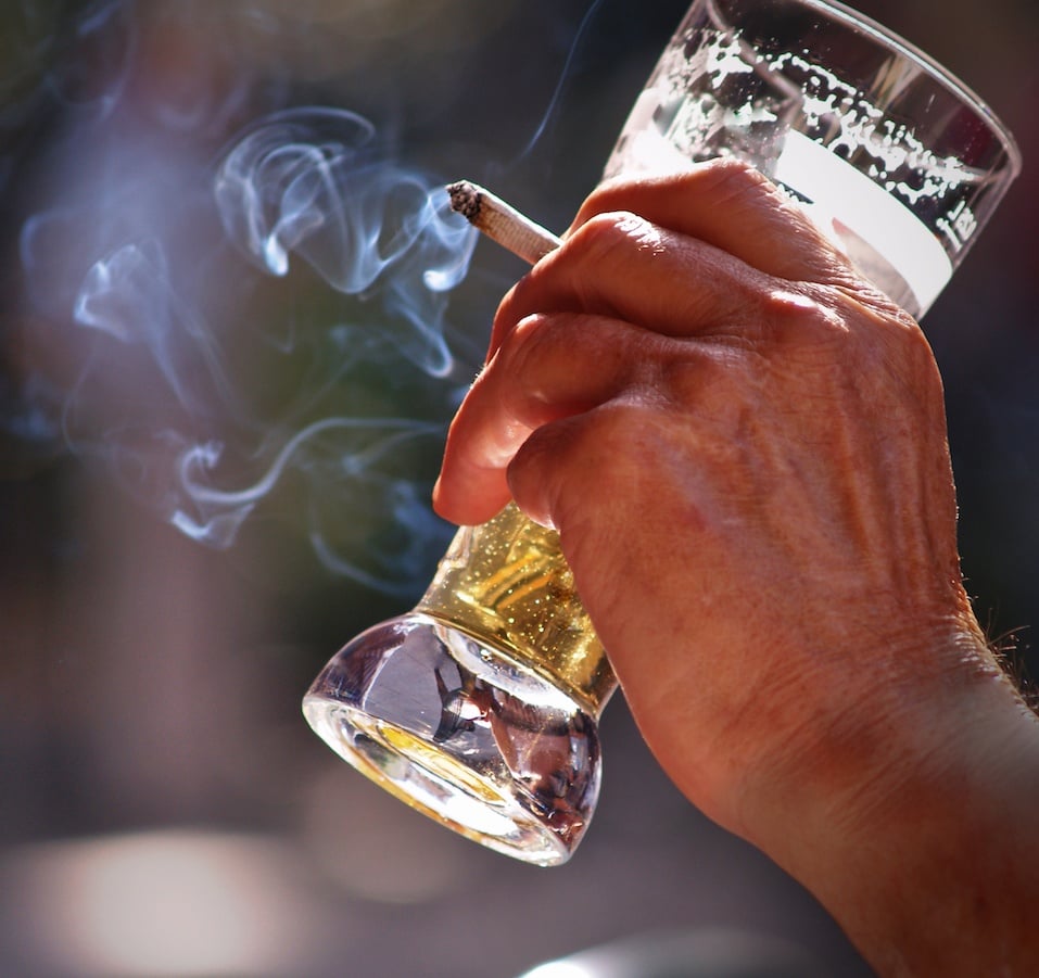 Man sitting at the table in outdoor pub Drinking beer and smoking Man sitting at the table in outdoor pub Drinking beer and smoking