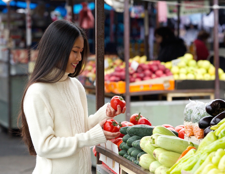 Portrait of a beautiful young woman smiling at the vegetable market