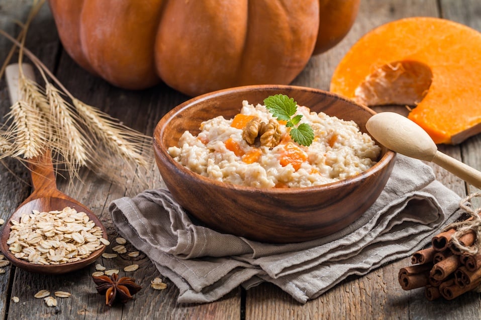 Breakfast oatmeal porridge with pumpkin in a wooden bowl on wooden background
