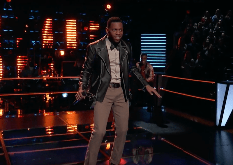 Chris Blue dancing and singing on stage in a leather jacket.