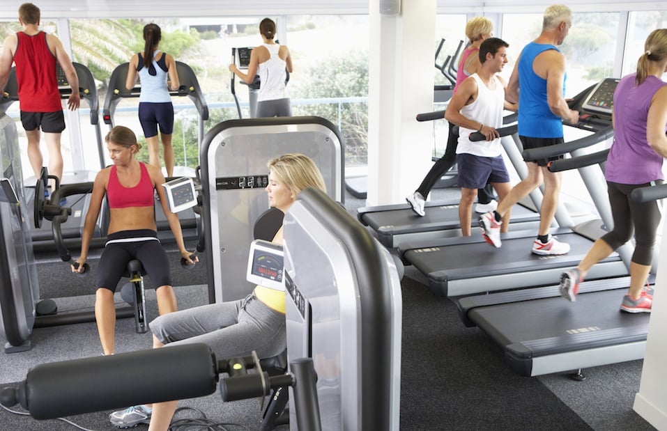 Busy Gym With People Exercising On Machines