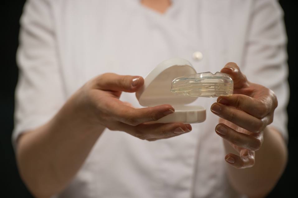 Female doctor orthodontist showing mouthguard teeth dental trainer
