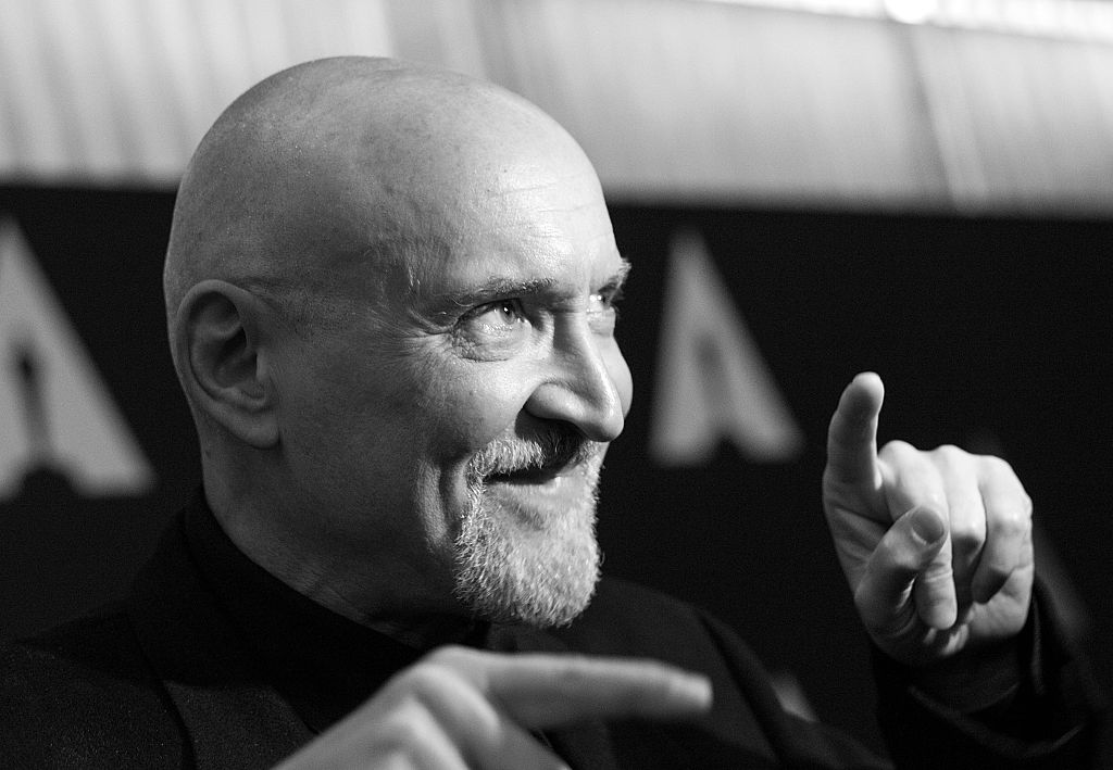 Frank Darabont in black and white, pointing both fingers in different directions and smiling