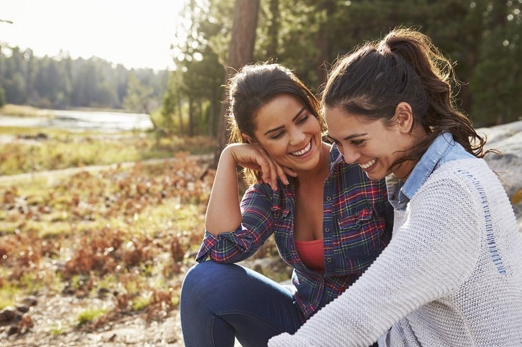Two women laughing together in the forest. two women laughing together